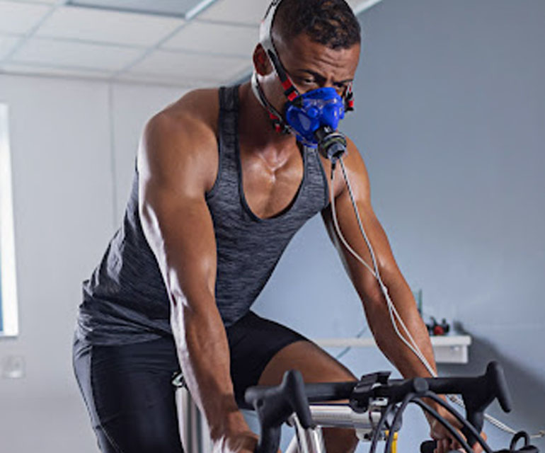 Man cycling with oxygen mask for VO₂ max test